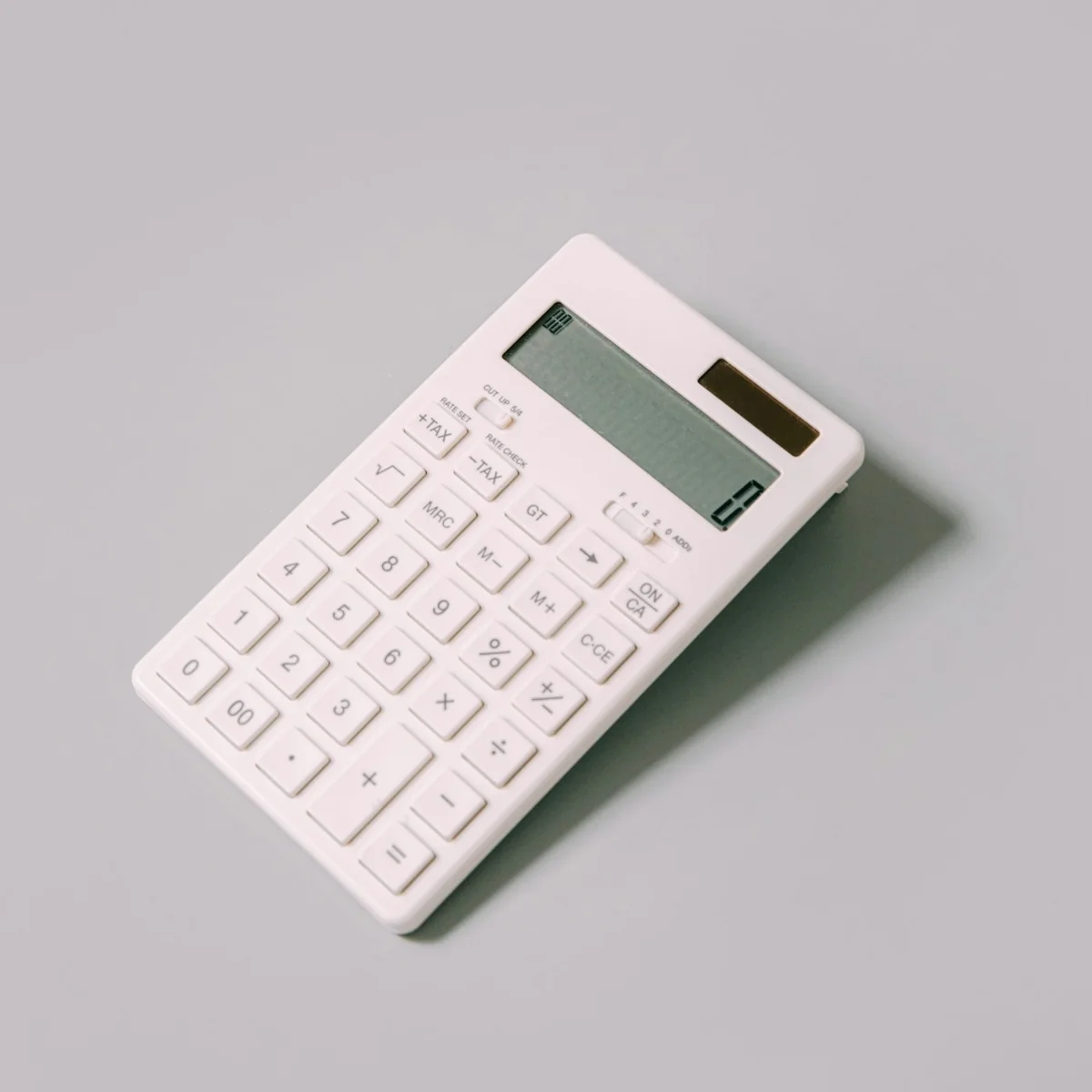 A white calculator on a plain desk